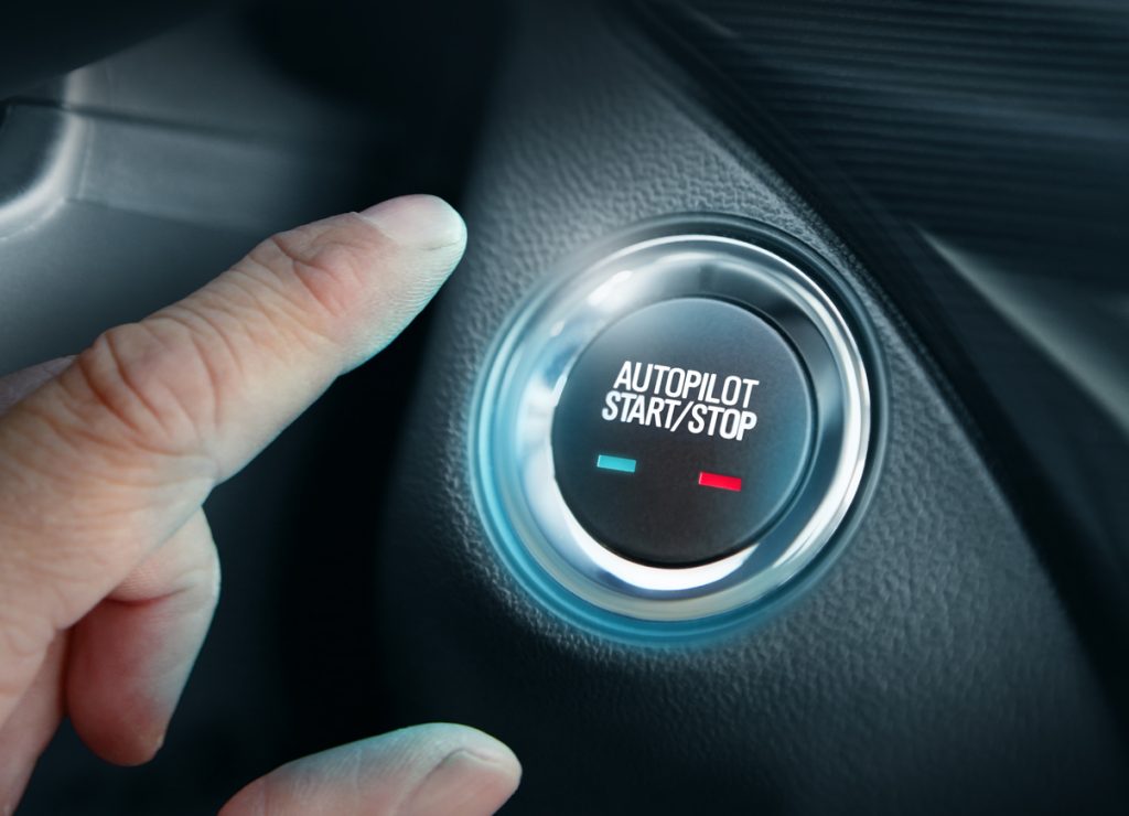 Hand pushing auto pilot button in autonomous car