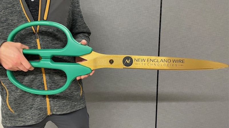 man holding giant scissors for ribbon cutting